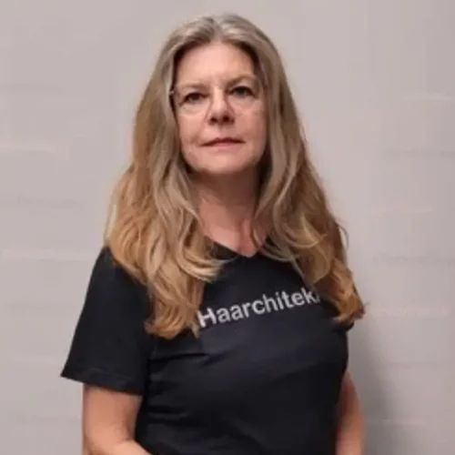Frau mit langen Haaren und Brille, die ein schwarzes „Haarchitekt“-T-Shirt trägt.