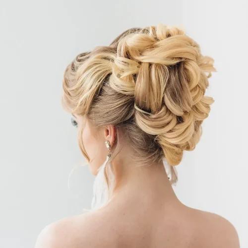 Frau mit einer eleganten blonden Hochsteckfrisur, die der Kamera den Rücken zukehrt.